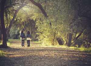 2 girls walking down a forest path