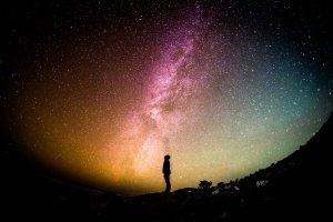 A person silhouetted against a galaxy