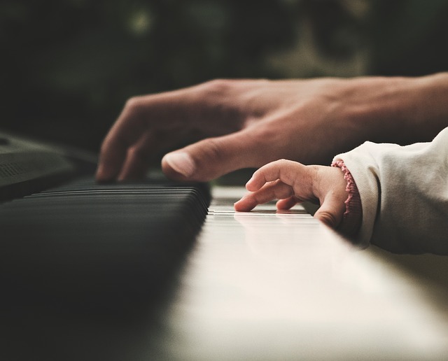 An adult and a child's hands on a piano.