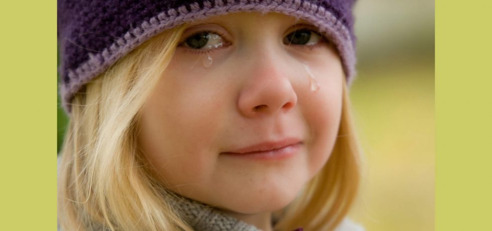 girl looking into the camera with tears rolling down her face, crying