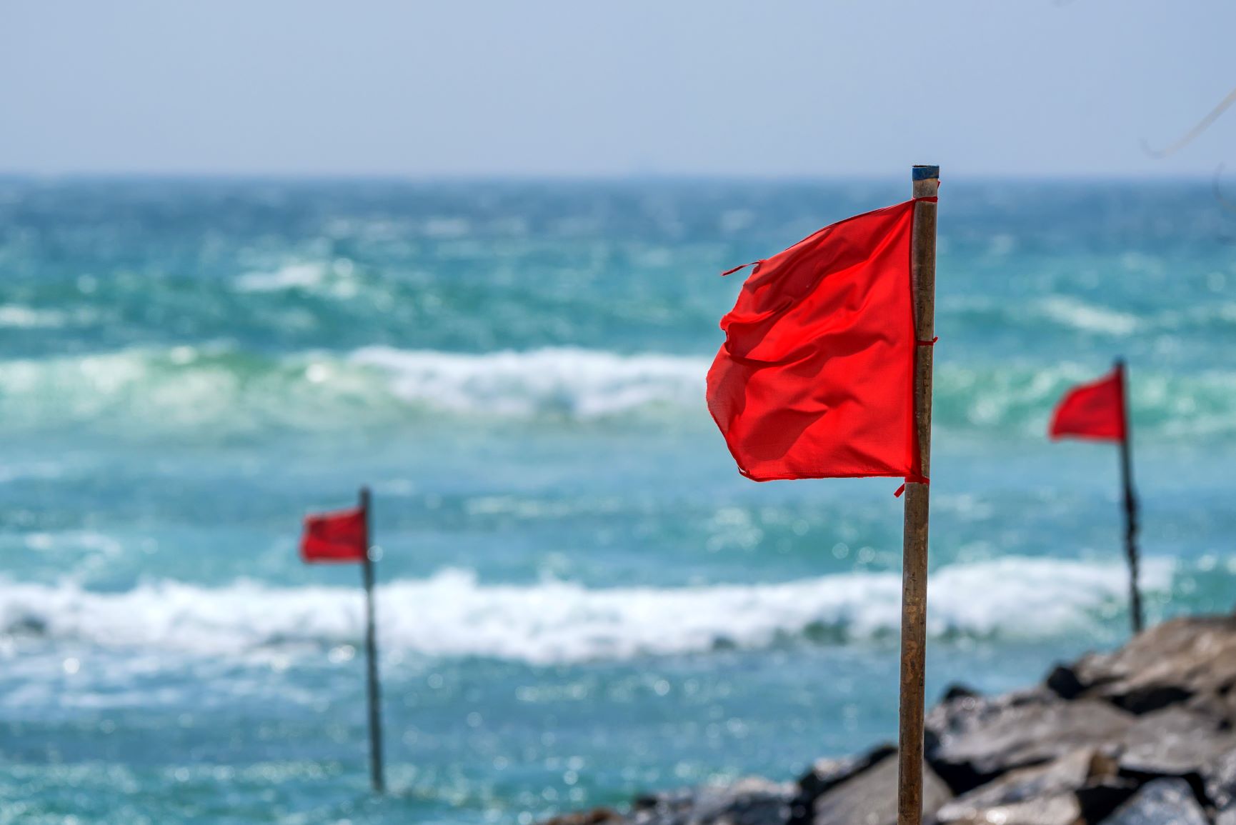 Red flags in rocks with the ocean right next to it.