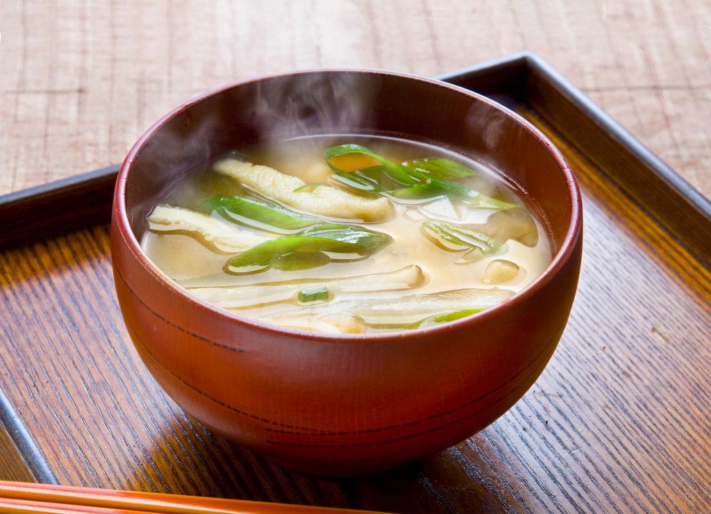 steaming miso soup in a dark red bowl