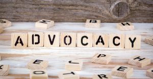 Wooden blocks similar to scrabble tiles spell out the word "advocacy" and are intended to simply be a literal and obvious way to represent the article