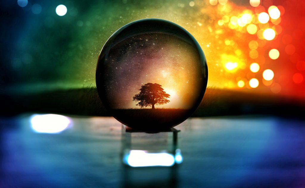 photo of a sparkling background. there is a tree in focus inside a crystal ball on a prism block.