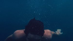 Man under water, bubbles rising to surface