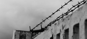 Barbed wire at the top of a cement fence